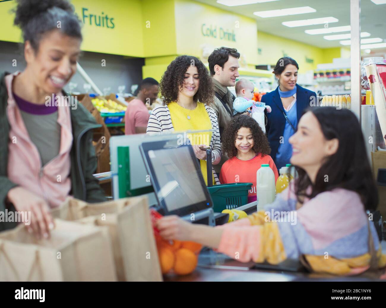 Cassiere che aiuta i clienti al checkout supermercato Foto Stock