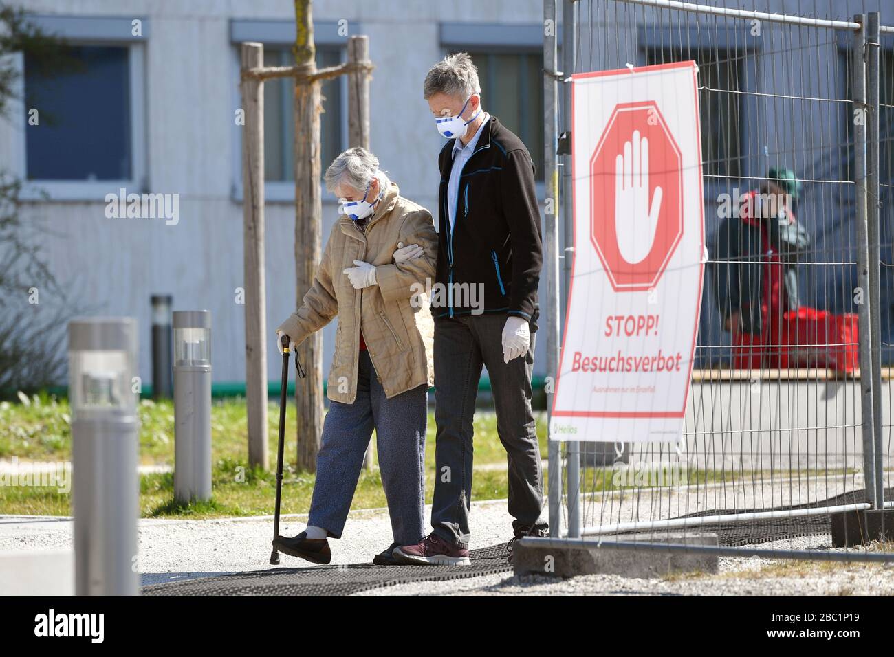 Monaco, Germania. 02nd Apr, 2020. Troppe infezioni da corona: Muenchner Helios Klinik cede le operazioni quotidiane. A causa di un gran numero di infezioni da corona tra pazienti e dipendenti, il Muenchner Klinik cede temporaneamente le normali operazioni ospedaliere. Anche la sala d'emergenza è interessata. Questo è il modo in cui le catene di infezione dovrebbero essere rotte. Un uomo più anziano e una donna più anziana vengono con maschere protettive, maschere facciali dall'ospedale passato una FERMATA di segno! BESUCHSV Amburgo HamburgERBOT il 2nd aprile 2020. | utilizzo credito mondiale: dpa/Alamy Live News Foto Stock