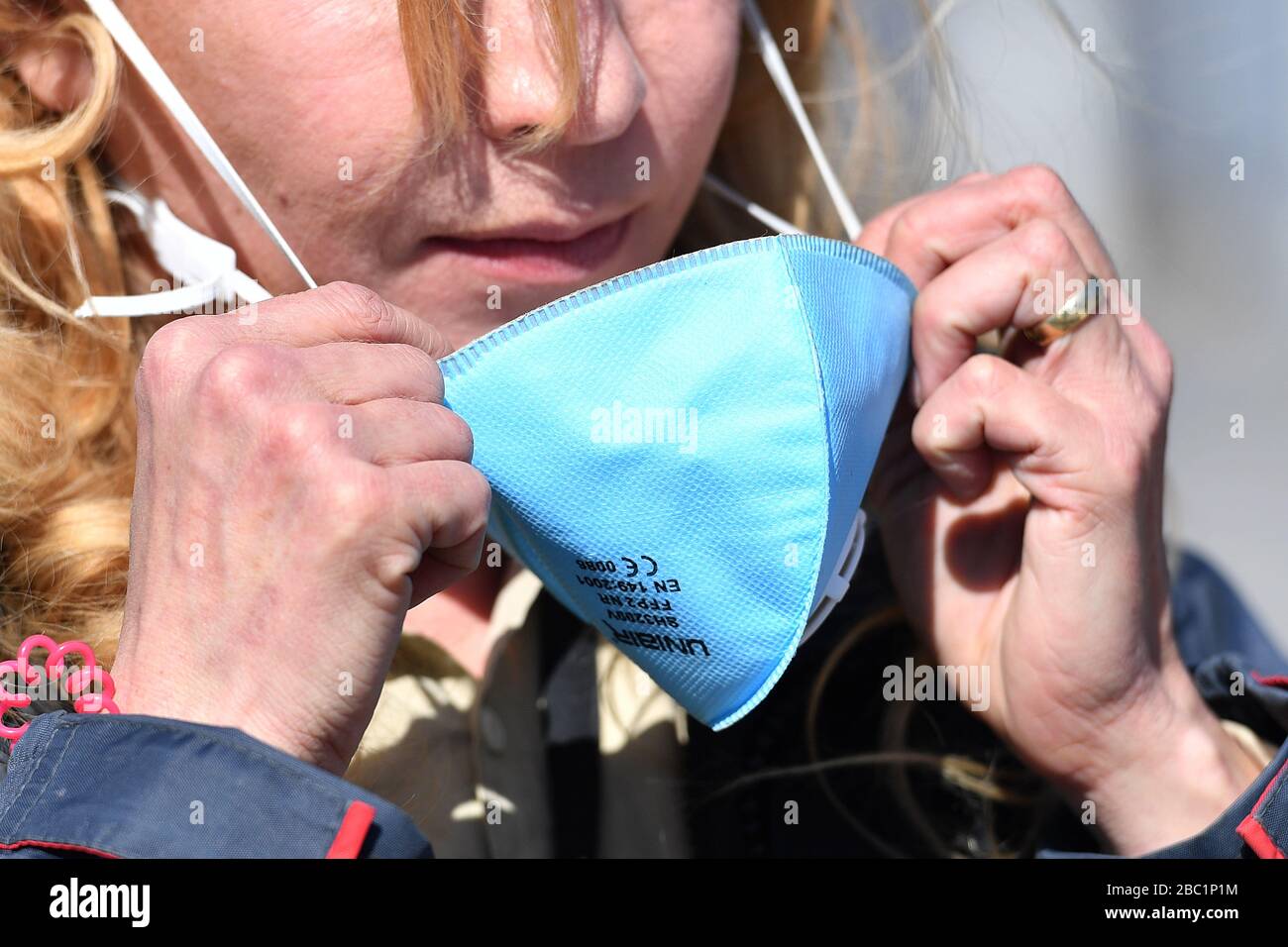 Monaco, Germania. 02nd Apr, 2020. Una donna mette una maschera facciale FFP2 sul suo viso. Maschera, maschera protettiva, maschera facciale, protezione antivirus, troppe infezioni da corona: Muenchner Helios Klinik cede le operazioni quotidiane. A causa di un gran numero di infezioni da corona tra pazienti e dipendenti, il Muenchner Klinik cede temporaneamente le normali operazioni ospedaliere. Anche la sala d'emergenza è interessata. Le catene di infezione sono da rompere il 2nd aprile 2020 | utilizzo in tutto il mondo credito: dpa/Alamy Live News Foto Stock