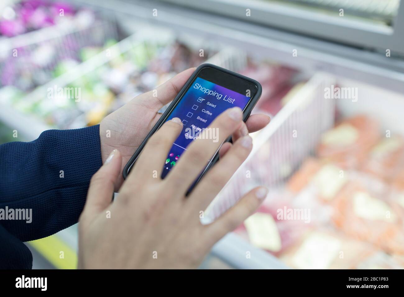 Chiudi donna con l'app per la lista degli acquisti di smart phone in supermercato Foto Stock