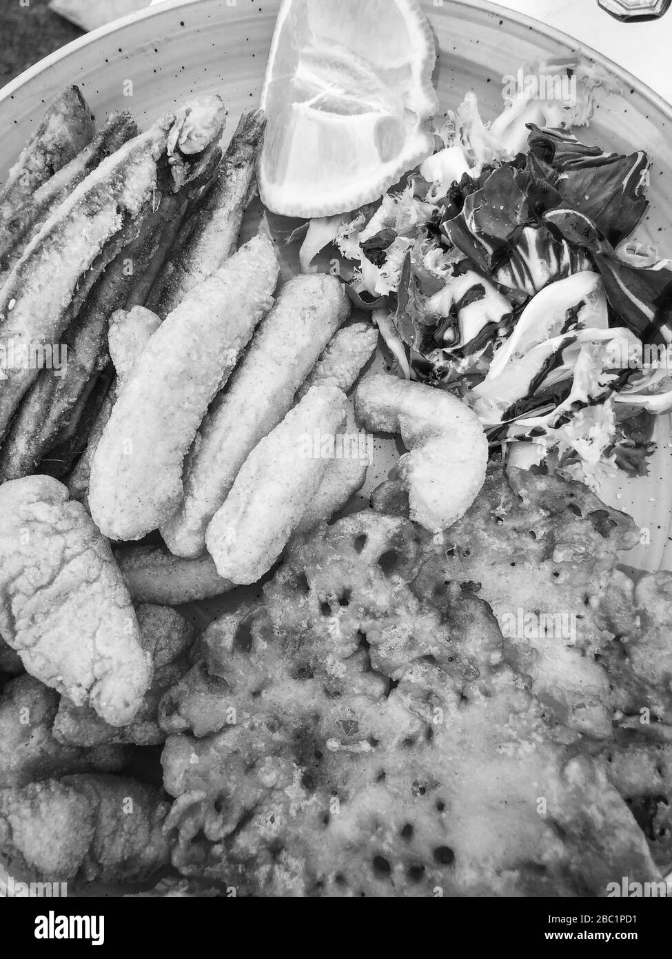 mischia i pesci fritti e il piatto di pesce con lattuga fresca e succo di limone Foto Stock