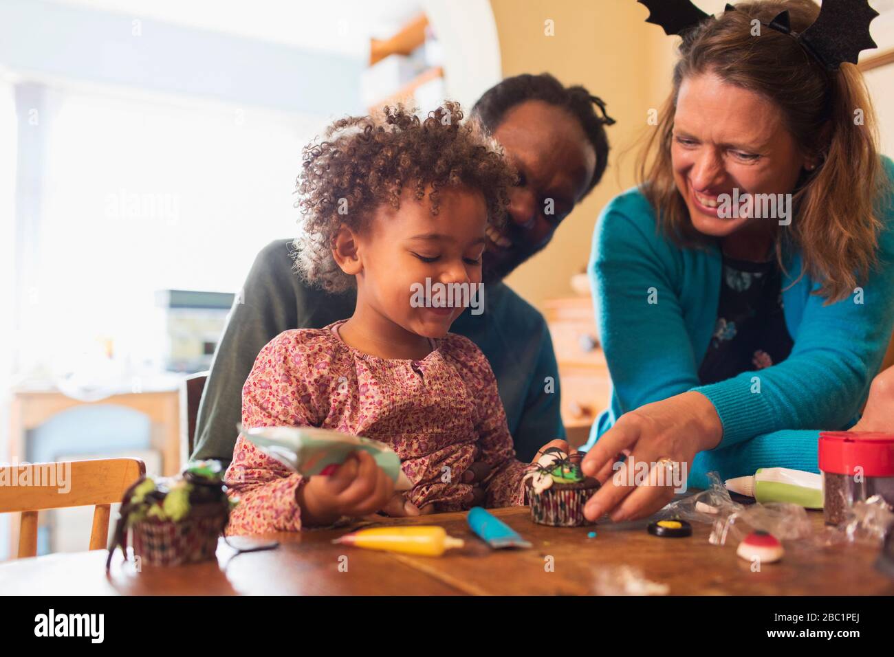Famiglia felice che decora i cupcakes di Halloween Foto Stock