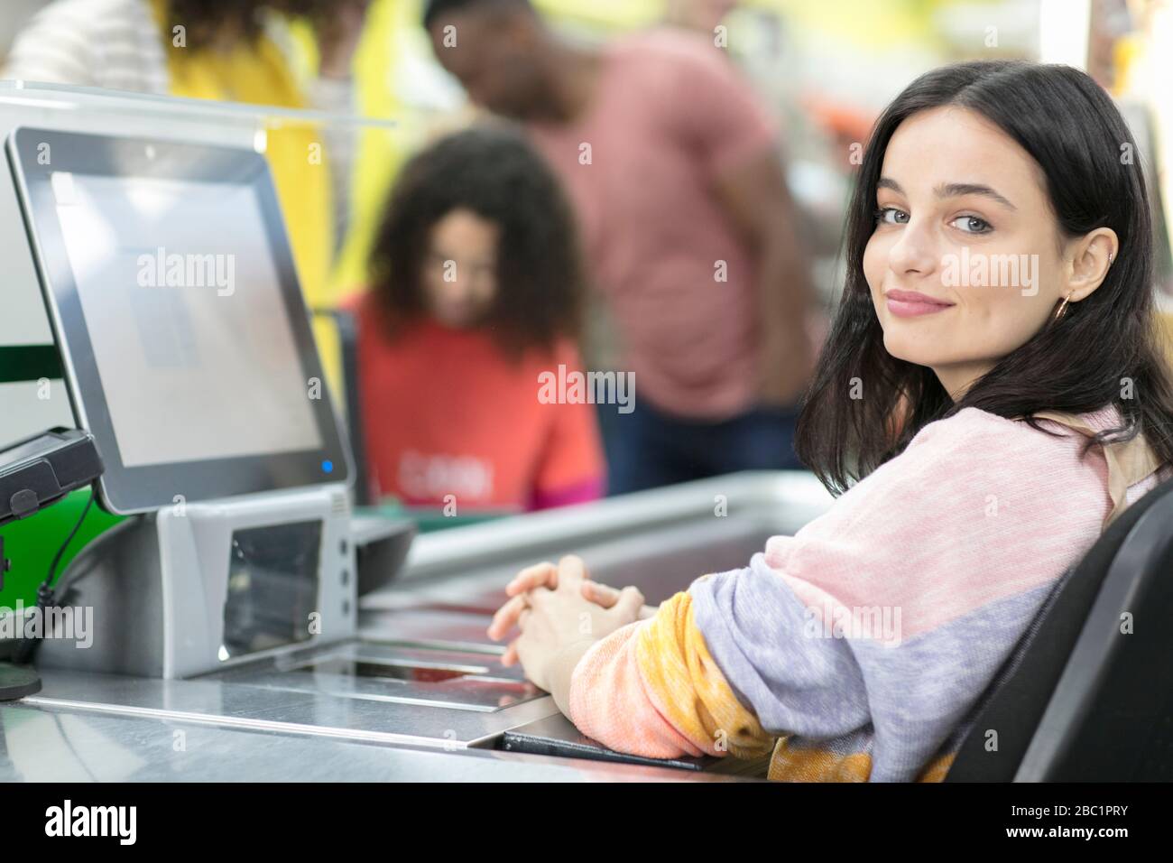 Ritratto sicuro cashier giovane femmina che lavora al checkout in supermercato Foto Stock