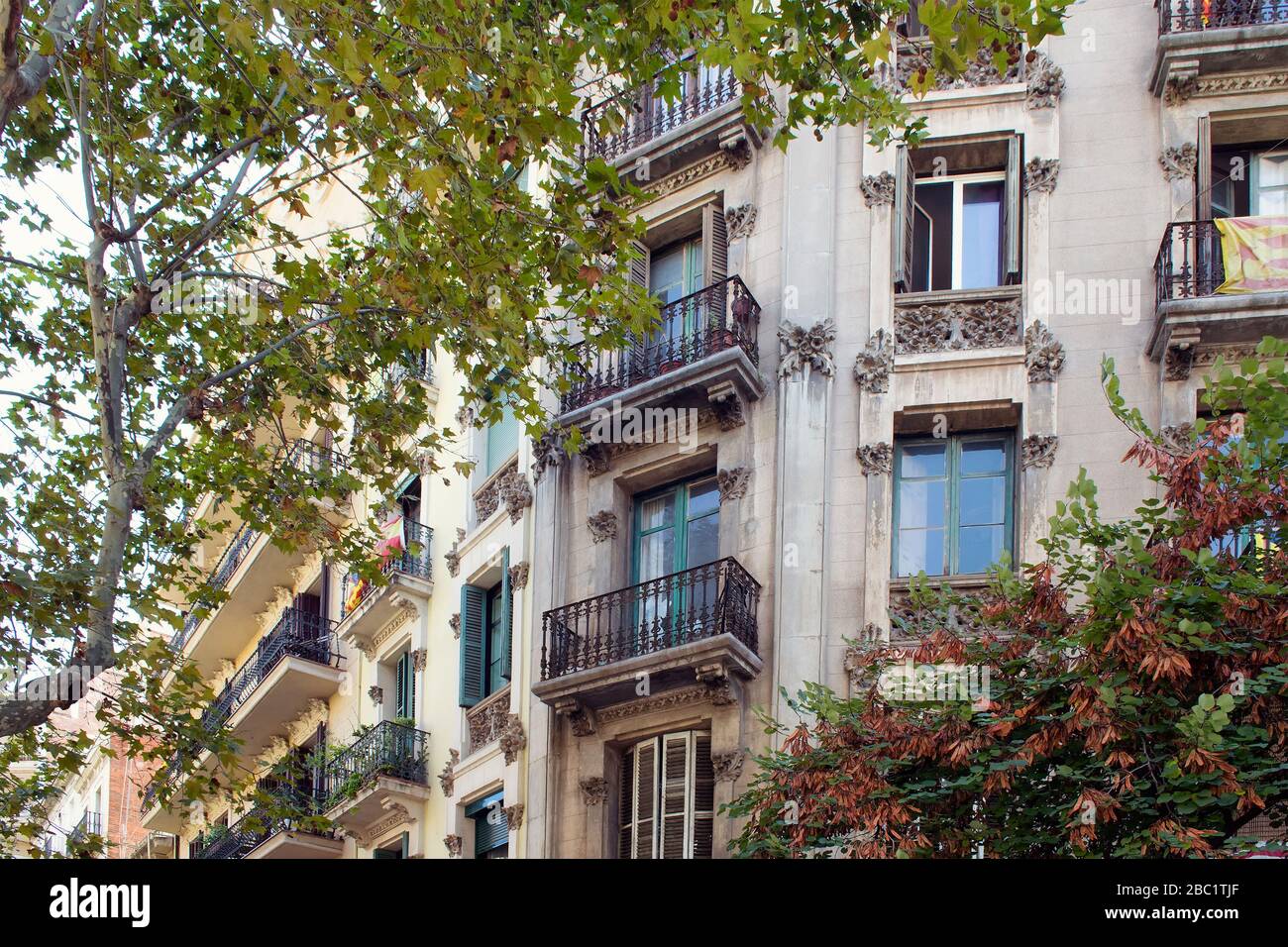 Vista ravvicinata del tradizionale e storico edificio residenziale tipico di Barcellona che mostra lo stile architettonico spagnolo. La bandiera catalana è appesa ad un bal Foto Stock