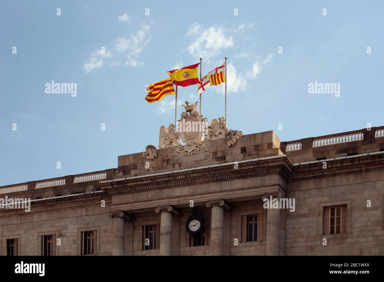 Vista delle bandiere spagnole e catalane che sventolano nella piazza della città chiamata 'Placa de Sant Jaume' nel quartiere 'Ciutat Vella' (quartiere Gotico) di Barcellona. È un Foto Stock