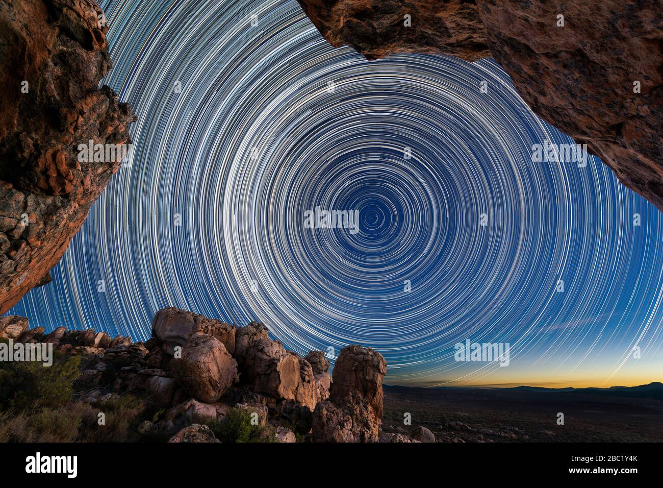 Una splendida fotografia notturna con i sentieri circolari stellari incorniciati da rocce drammatiche in primo piano, prese nelle montagne di Cederberg in Occidente Foto Stock