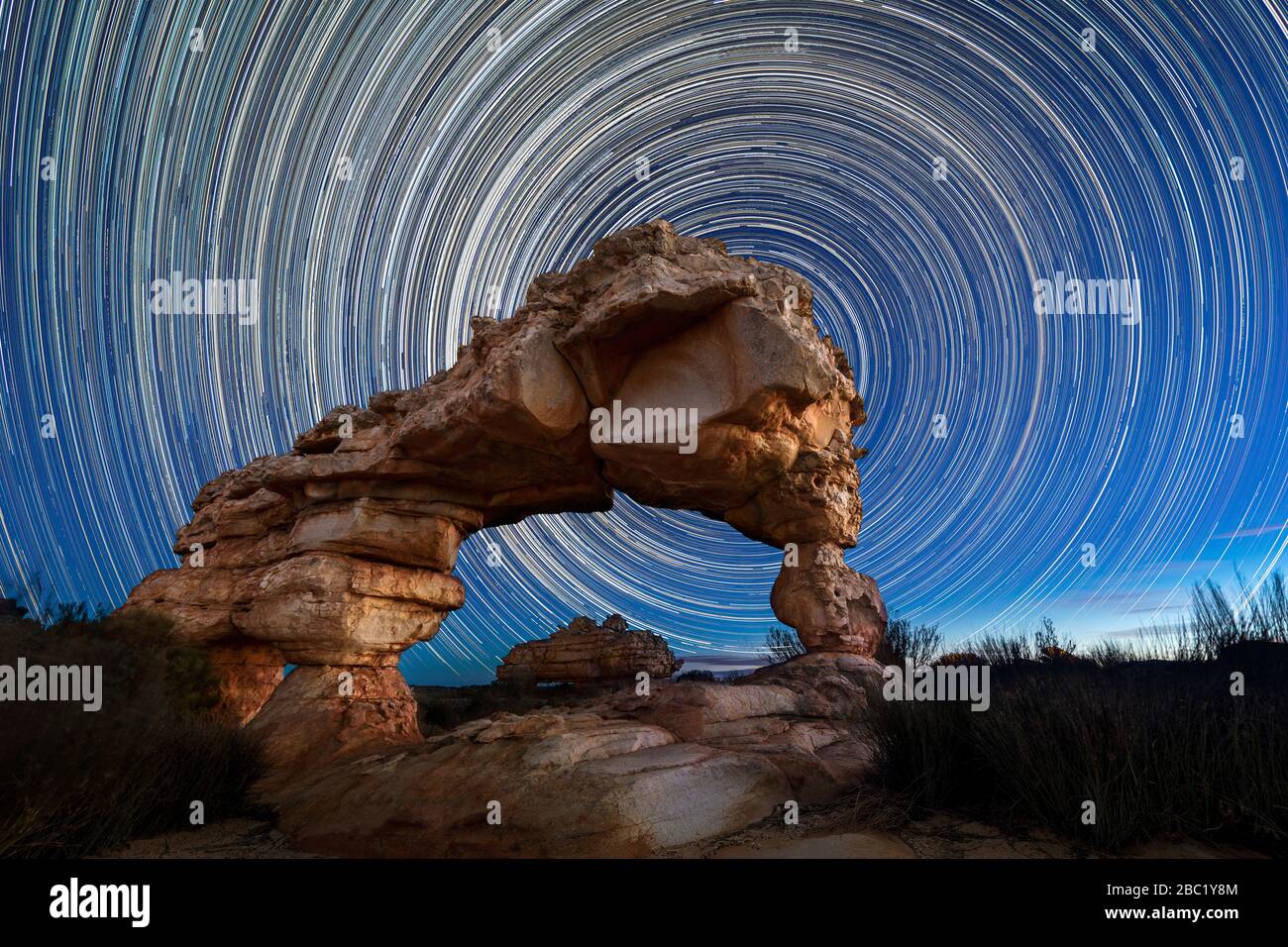 Una splendida fotografia notturna del cielo con percorsi circolari stellari dietro un suggestivo Rock Arch, presa nelle montagne di Cederberg nel Capo Occidentale, Sud AF Foto Stock