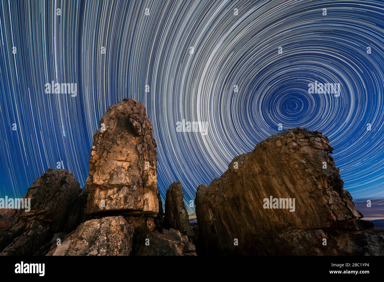 Una bella fotografia di cielo notturno con percorsi a stella circolare contro un cielo blu profondo con maestose rocce drammatiche in primo piano, presa nel Cedersb Foto Stock