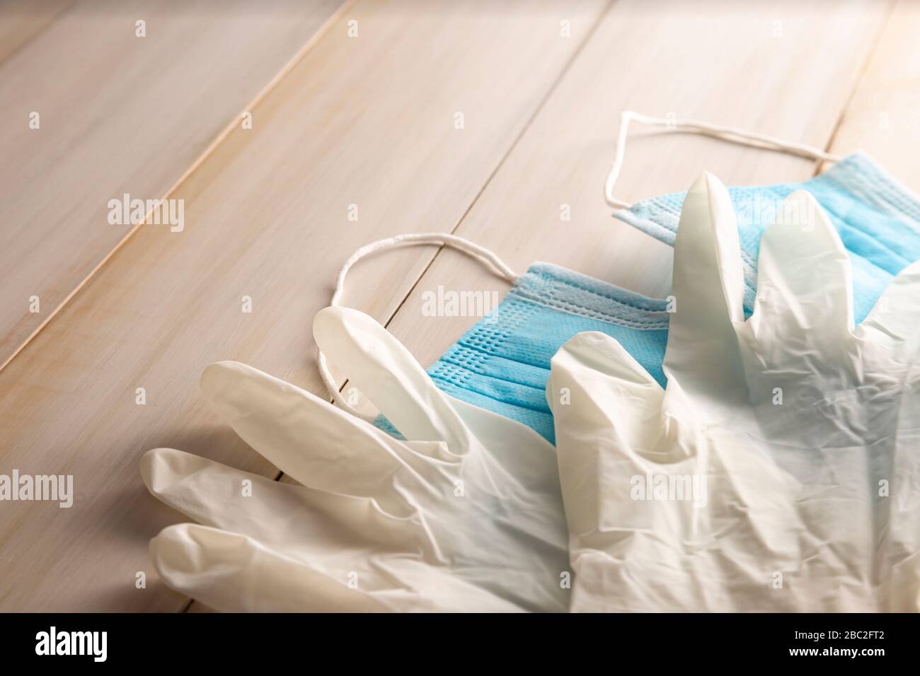 guanti in lattice per uso medico e maschere facciali per la protezione su sfondo in legno. Utile per il concetto di prevenzione pandemica Foto Stock