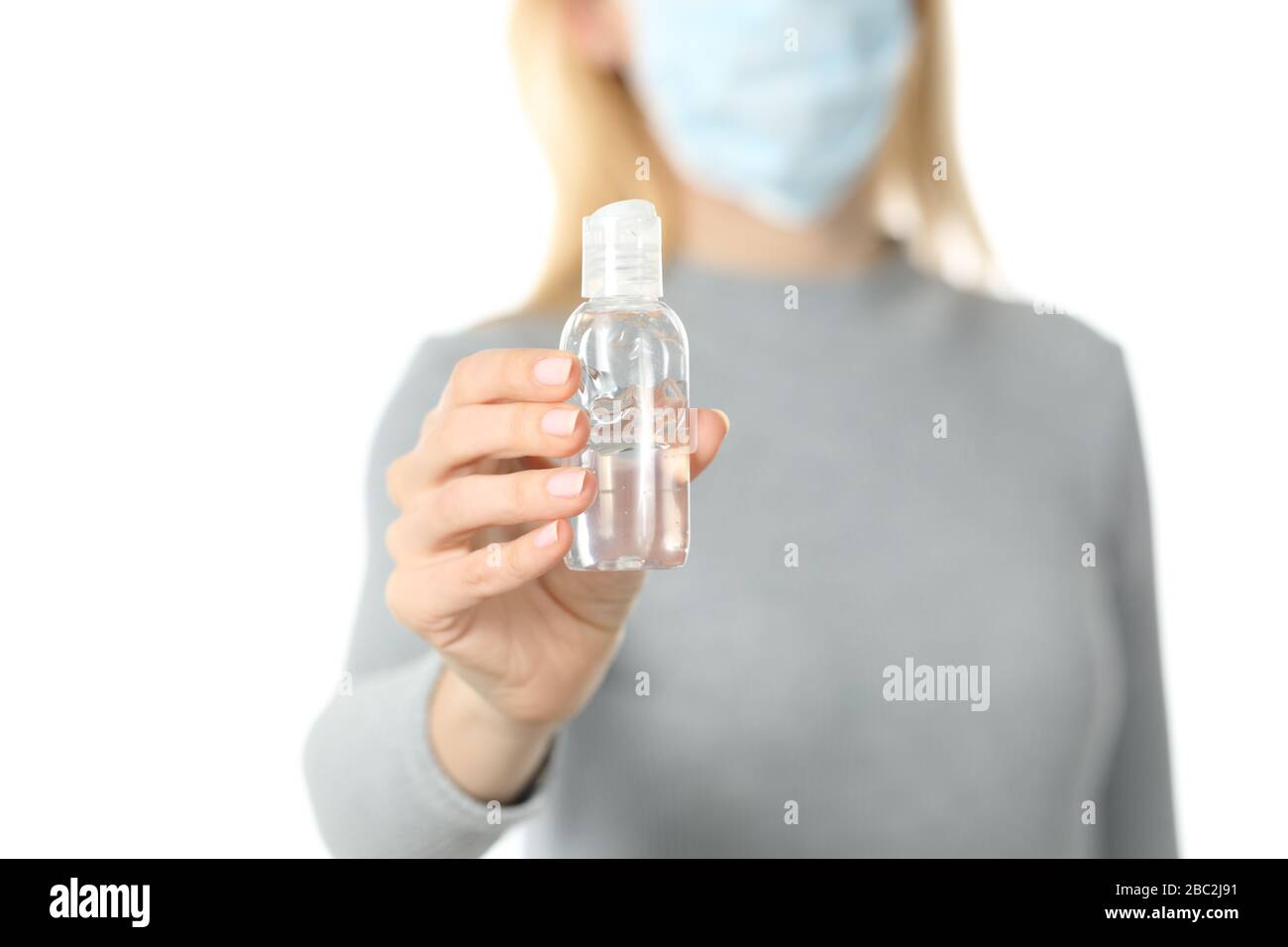Primo piano di donna con maschera protettiva che mostra igienizzatore per mani isolato su sfondo bianco Foto Stock