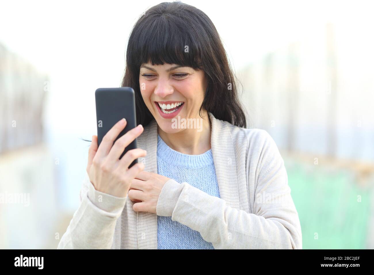 Donna adulta felice ridendo controllo del contenuto di smartphone su un ponte Foto Stock