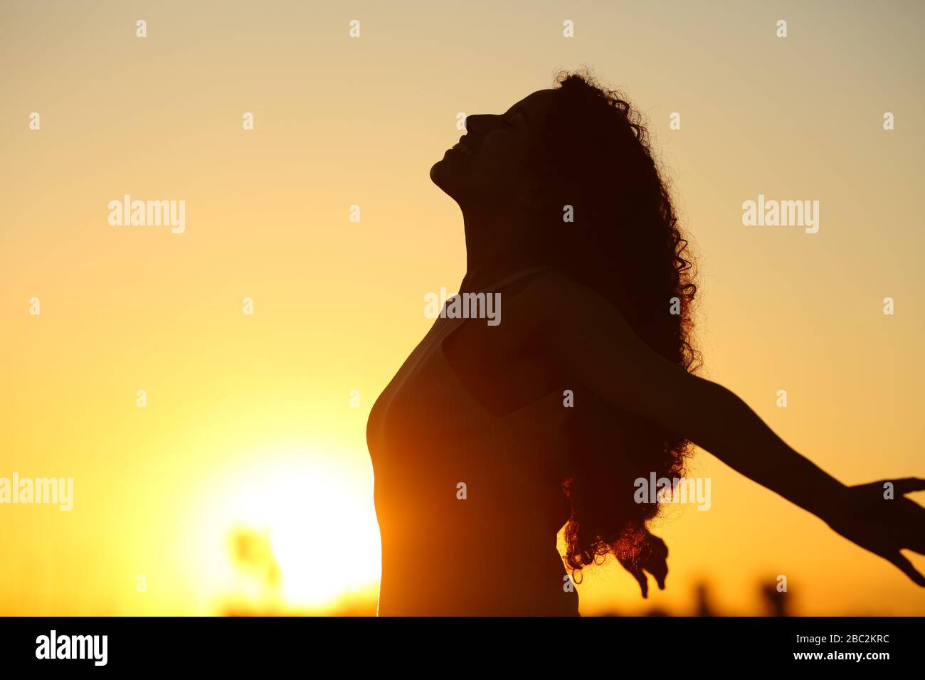 Vista laterale silhouette di una signora che respira aria profondamente fresca al tramonto Foto Stock
