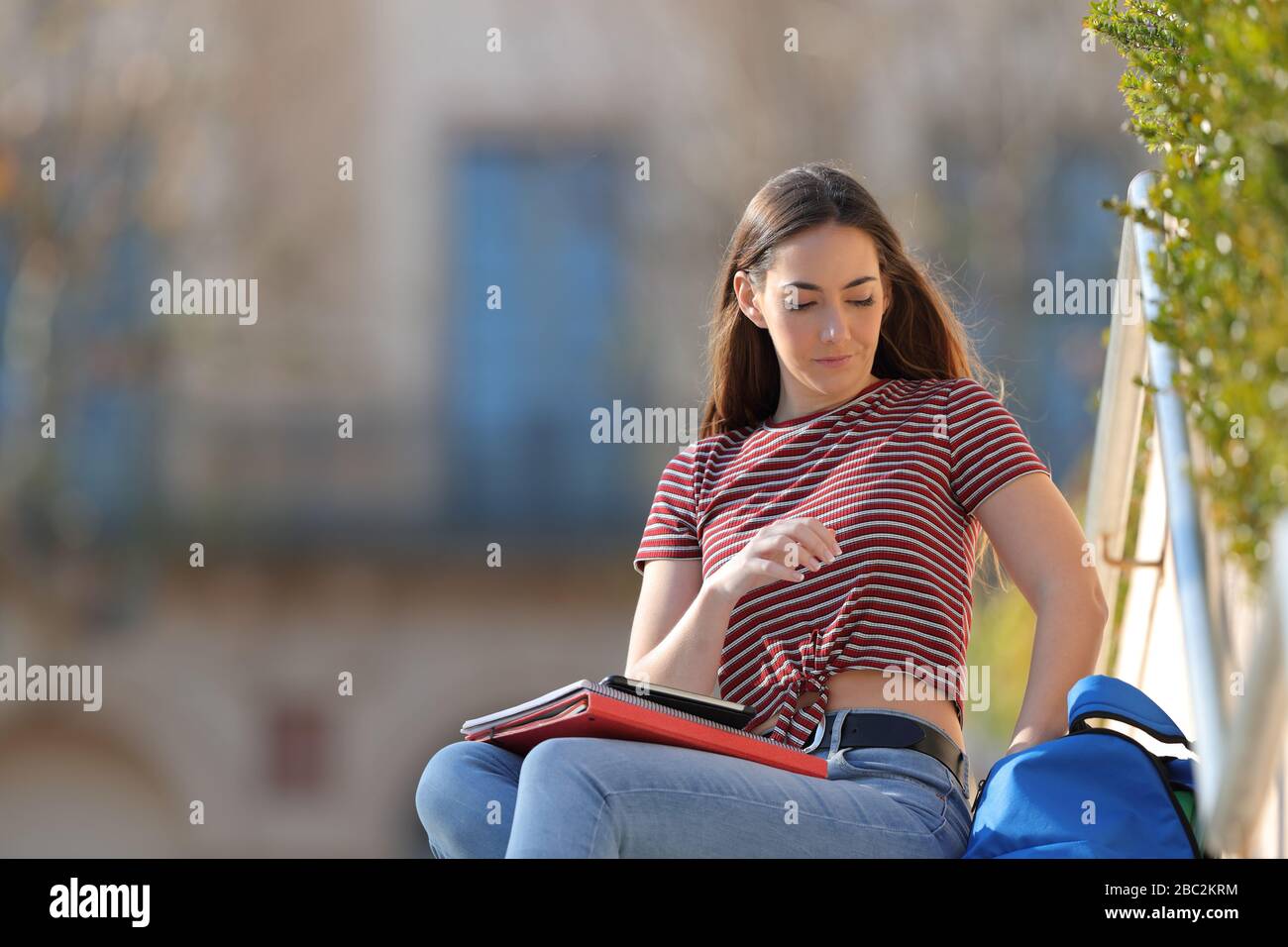 Gli studenti che prendono le cose dallo zaino seduto in un campus Foto Stock