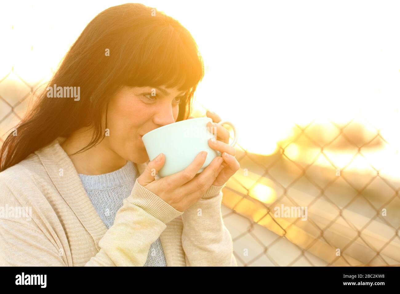 Buona donna adulta bevendo caffè al tramonto in strada Foto Stock