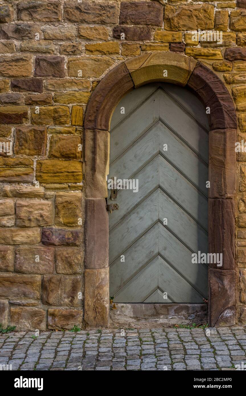 pietra arenaria storica città muro con porta in legno e telaio porta con arenaria rotonda arco scolpito con speciale serratura Foto Stock