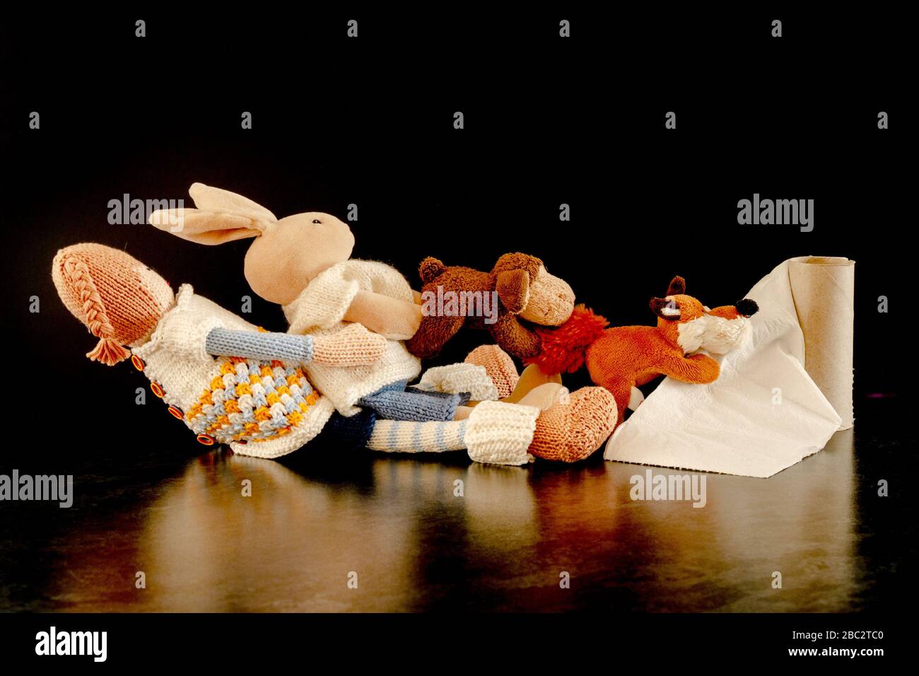 Immagine concettuale che illustra la mancanza di rotolo di servizi igienici come molti giocattoli cuddly provano a appendere sugli ultimi pezzi di carta igienica Foto Stock