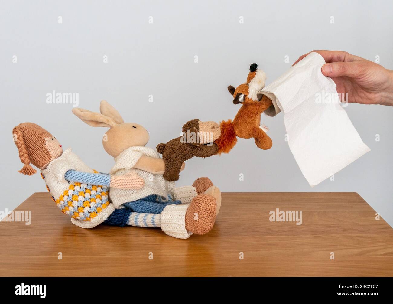 Immagine concettuale che illustra la mancanza di rotolo di servizi igienici come molti giocattoli cuddly provano a appendere sugli ultimi pezzi di carta igienica Foto Stock