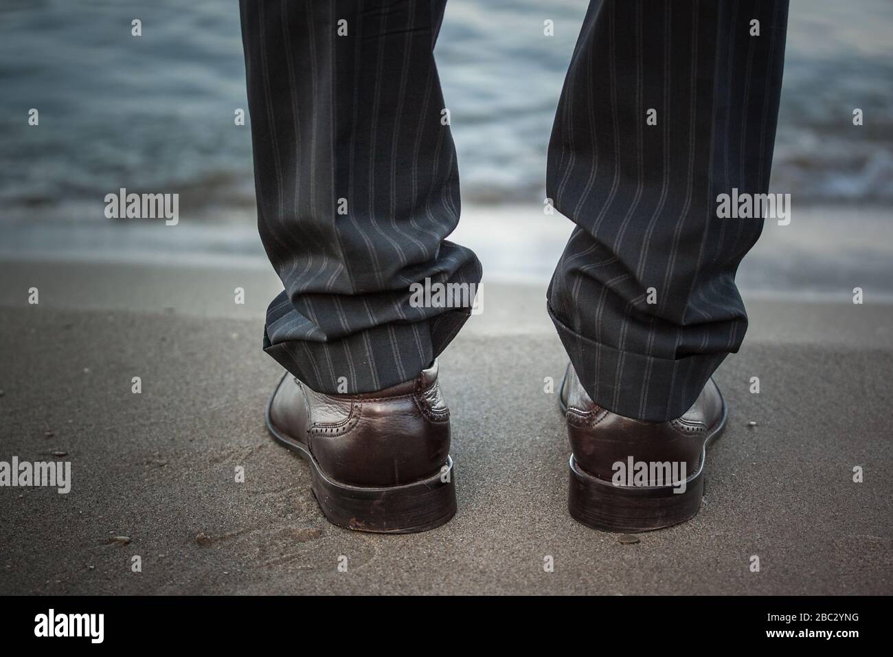 I piedi di un uomo in pantaloni neri e scarpe si erige vicino al mare Foto  stock - Alamy