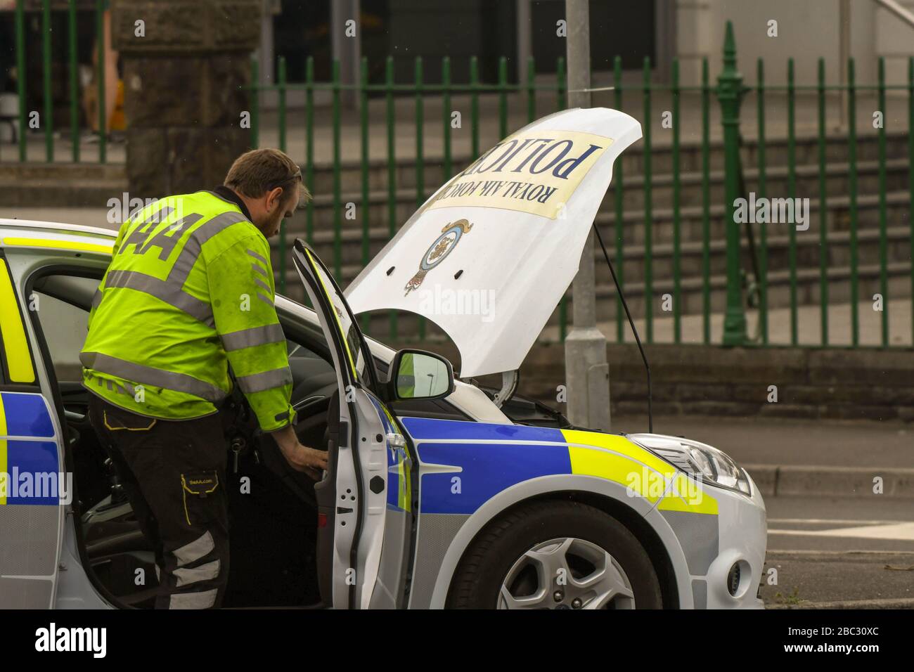 SWANSEA, GALLES - LUGLIO 2018: Meccanico dell'AA che partecipa a una vettura di pattuglia di polizia RAF rotta a Swansea, Galles. Foto Stock