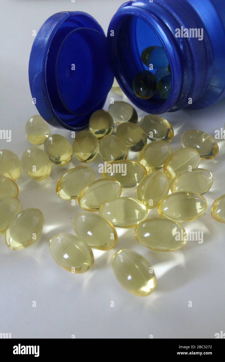 Bottiglia blu di capsule di vitamina omega 3 olio di pesce con qualche fuoriuscita sul primo piano bianco Foto Stock