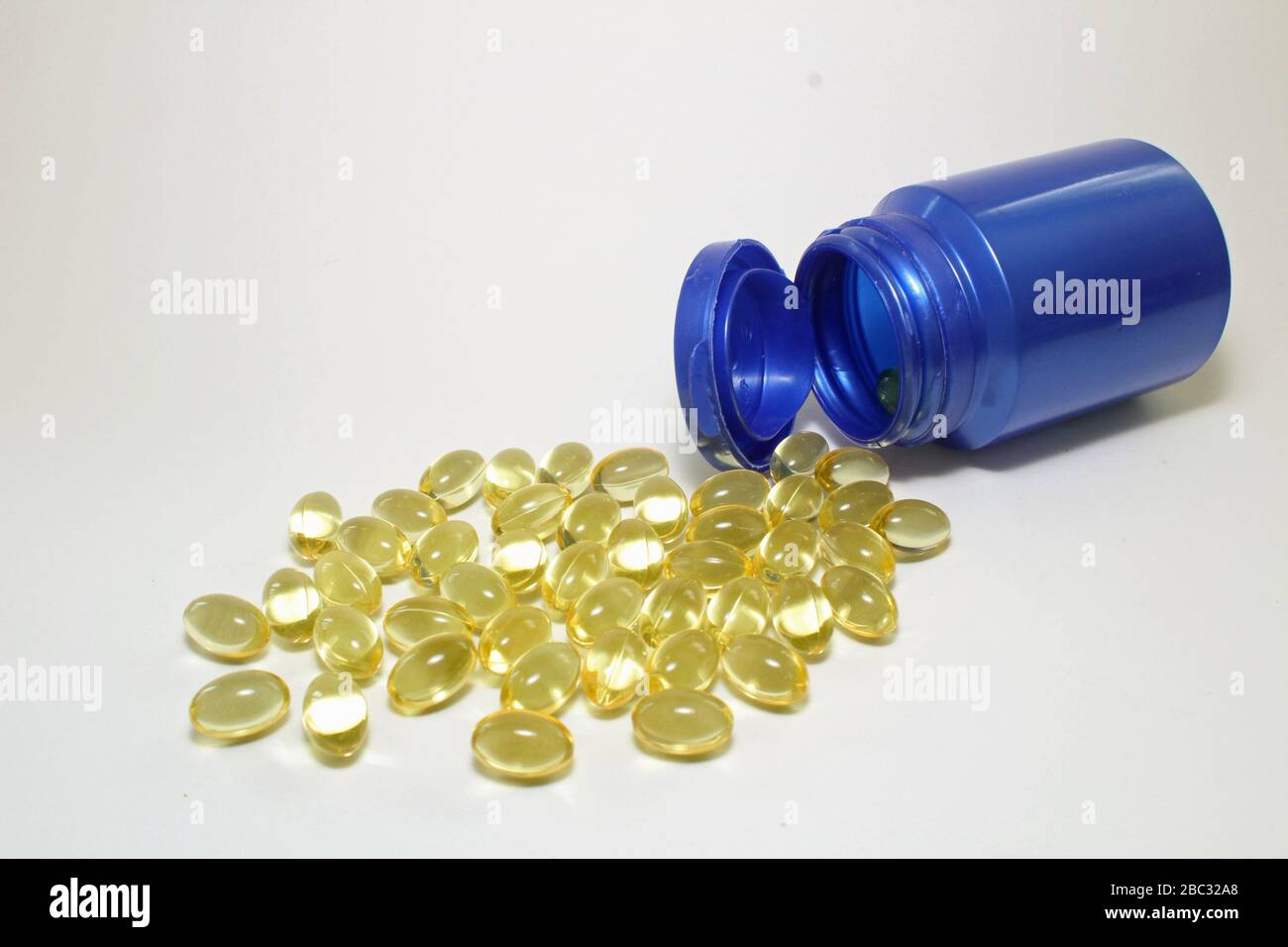 Bottiglia blu di capsule di vitamina omega 3 olio di pesce con qualche fuoriuscita sul primo piano bianco Foto Stock