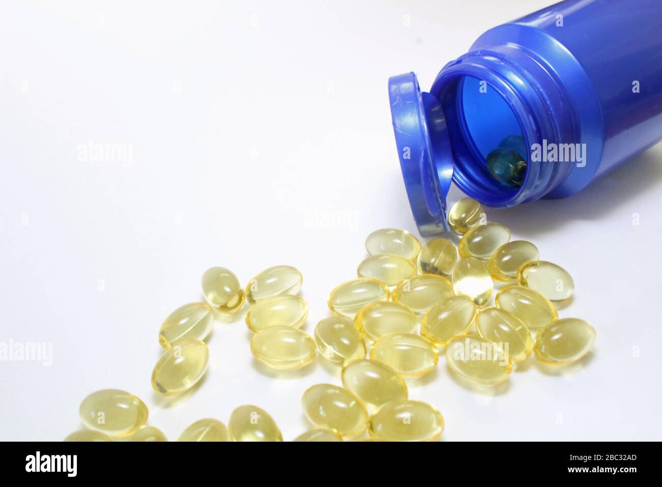 Bottiglia blu di capsule di vitamina omega 3 olio di pesce con qualche fuoriuscita sul primo piano bianco Foto Stock