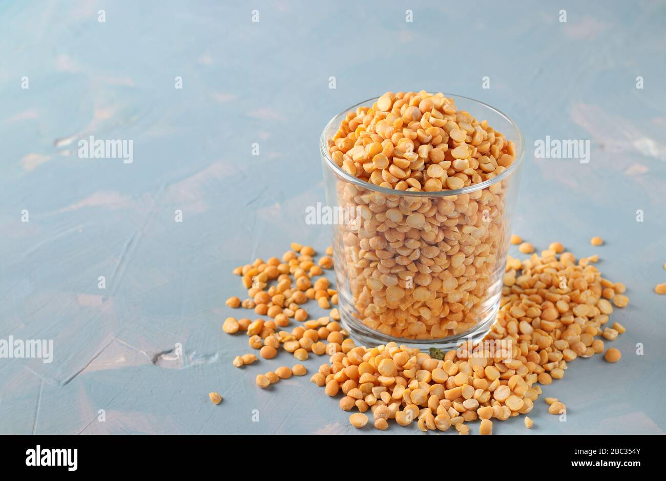 Piselli secchi grano in un vetro e tavolo su sfondo azzurro Foto Stock