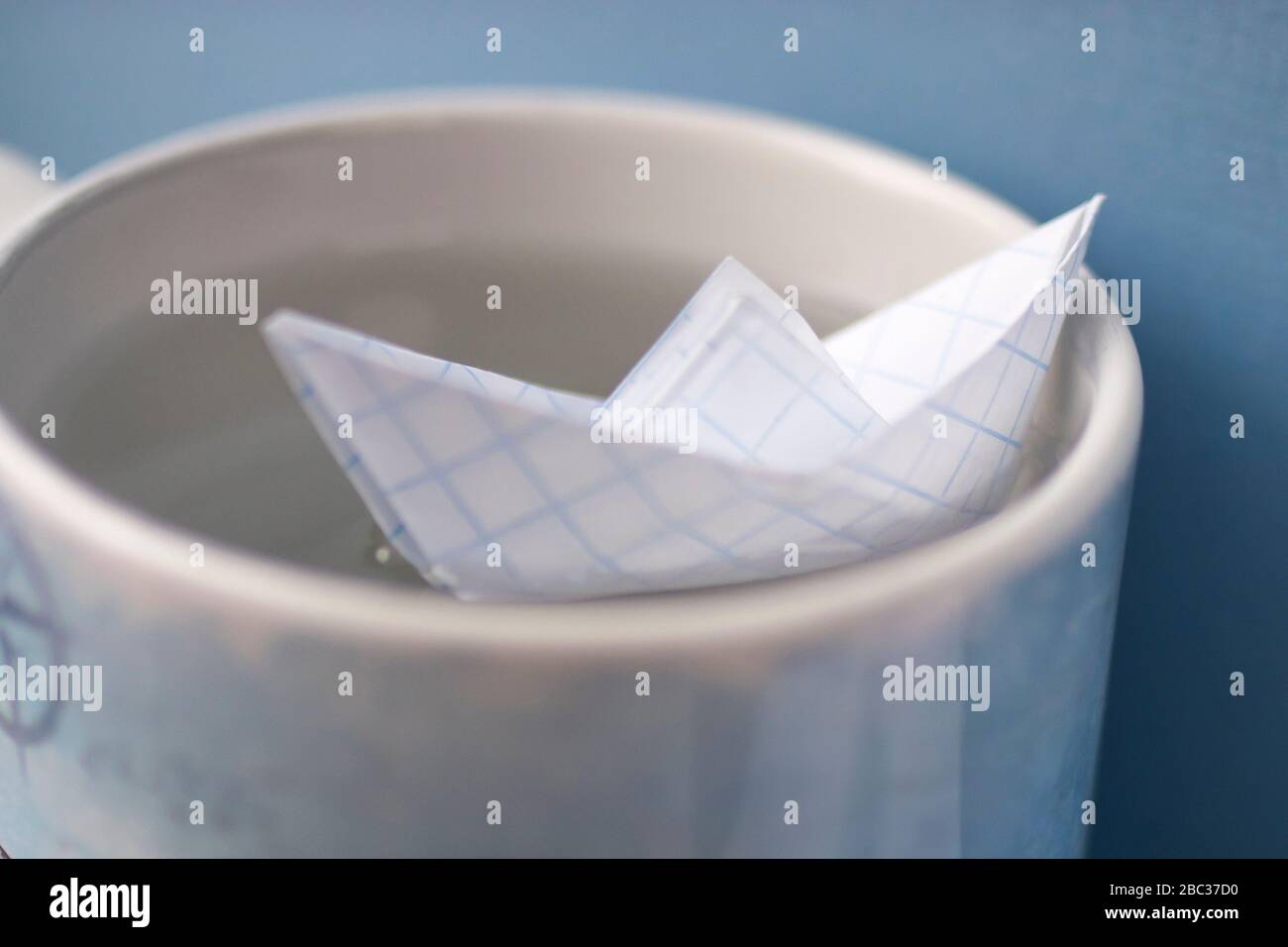 Carta a scacchi barca in una tazza con acqua. Nitidezza selettiva. Spazio di copia Foto Stock