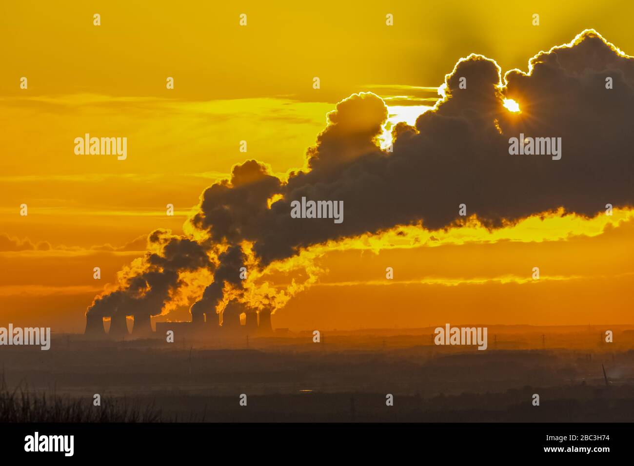 Vista distante dai ludi dello Yorkshire, Regno Unito delle torri di raffreddamento di una centrale elettrica vicino a Drax nel North Yorkshire, con il tramonto dietro il percorso del vapore Foto Stock