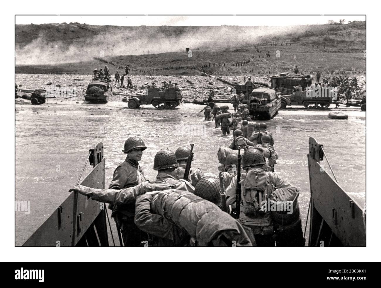 Omaha Beach Landng CRAFT D Day WW2 truppe GI americane sbarcano D-Day WW2 GIUGNO 6th 1944 GI Soldiers Group americano in una spiaggia di sbarco sotto il fuoco da parte Nazi Wehrmacht armi posizionamenti in Normandia Francia durante l'invasione alleata, 6 giugno 1944. Lungo un tratto di costa di 80 km nel nord della Francia, più di 160.000 truppe alleate hanno stormato Utah Beach e quattro altre spiagge che quel giorno hanno preso piede nell'Europa nazista continentale. Alla fine dell'invasione del D-Day, più di 9.000 di queste truppe alleate erano morte o ferite - la maggior parte di loro americani. Seconda guerra mondiale Foto Stock