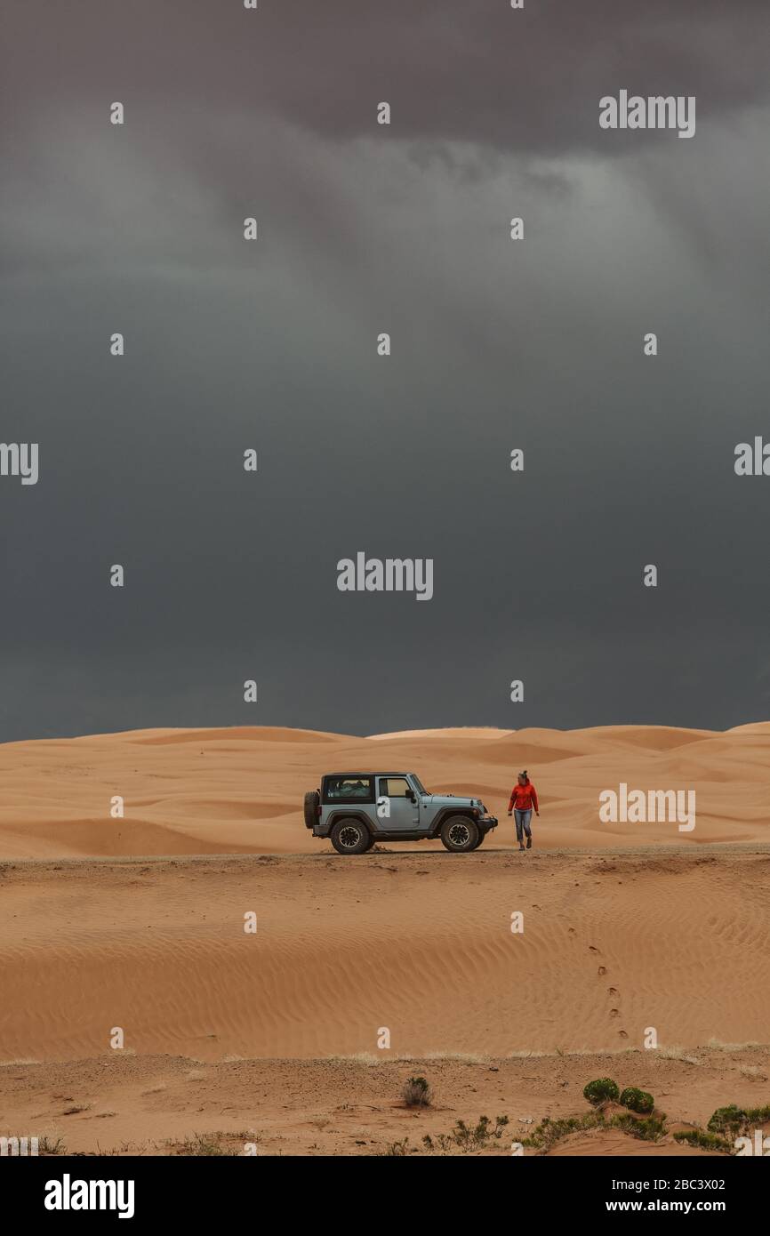 donna turistica esce dalla jeep nelle dune di sabbia tempestose dello utah Foto Stock