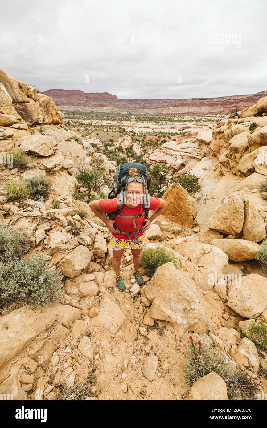 la femmina escursionista con le mani sui fianchi guarda la macchina fotografica mentre si fa un'escursione nello utah Foto Stock