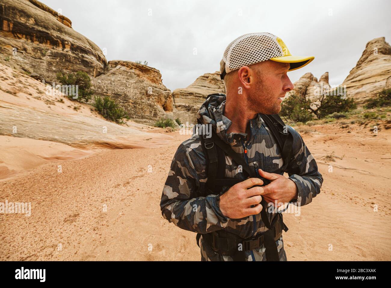 l'escursionista guarda a sinistra e fibbia la sua fascia toracica di zaino nel deserto Foto Stock