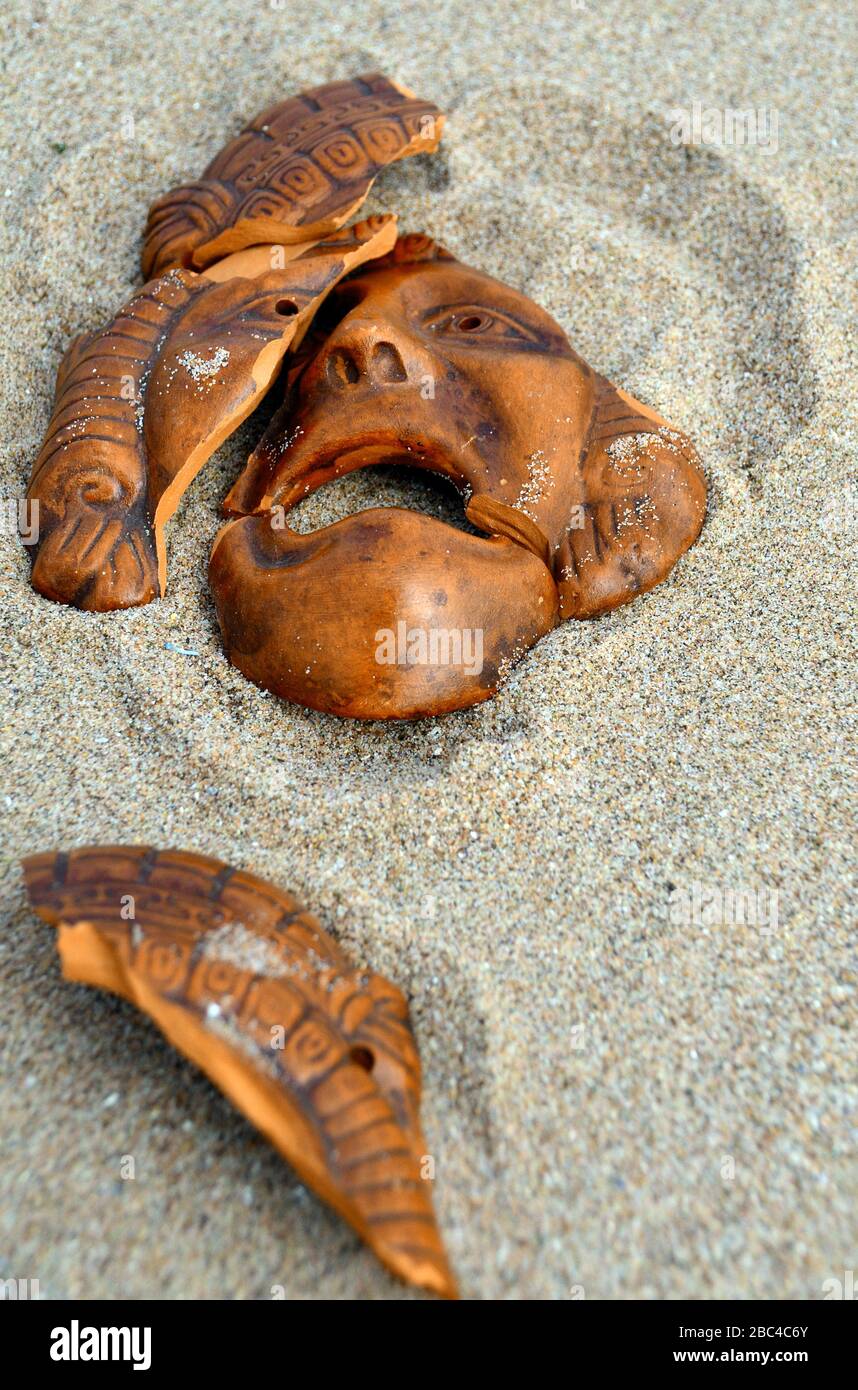 rotta tragica maschera di argilla greca giacente nella sabbia Foto Stock