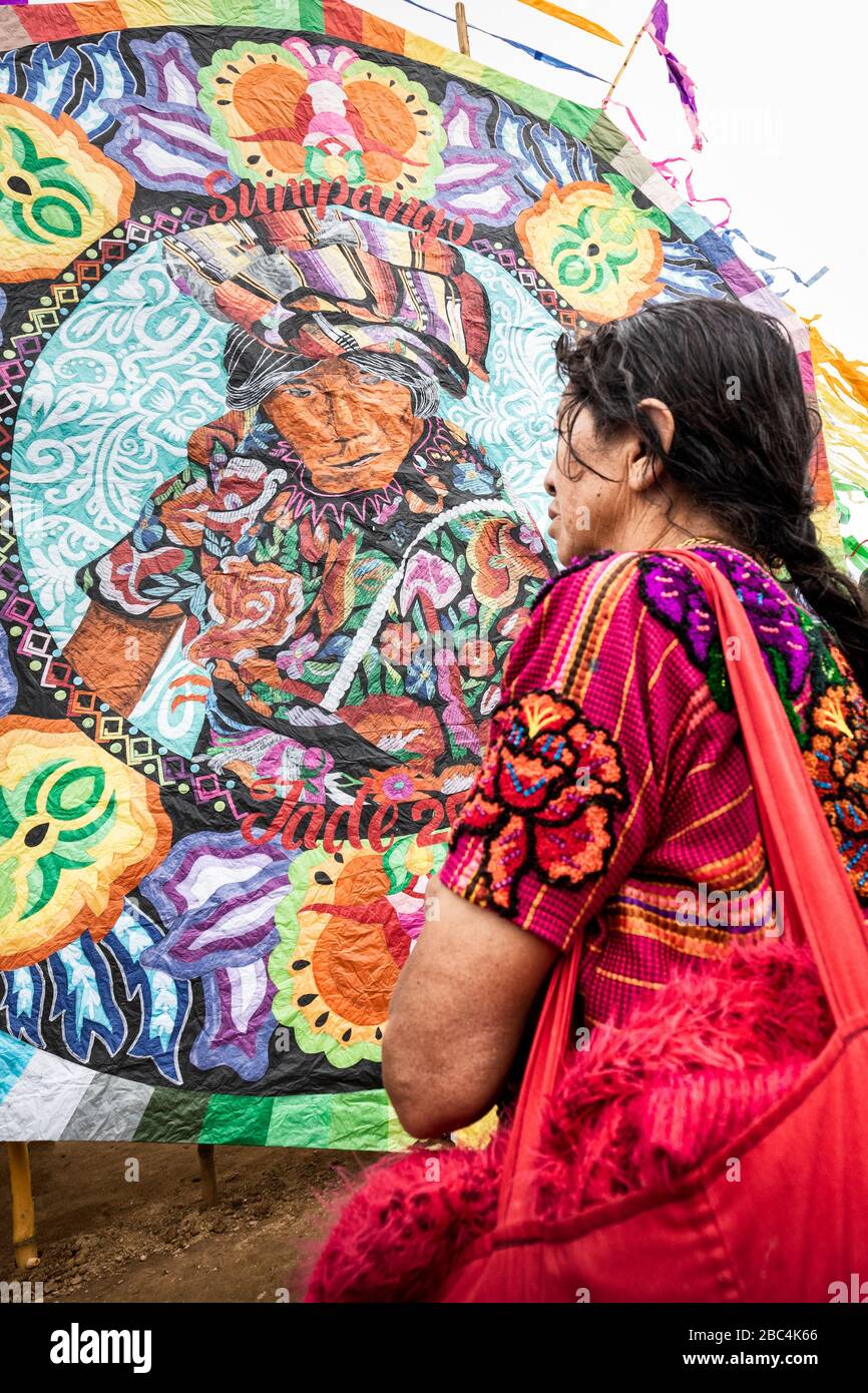 Figura su un grande barrilete sembra guardare giù ad una donna al Sumpango Kite Festival il giorno dei morti in Guatemala. Foto Stock