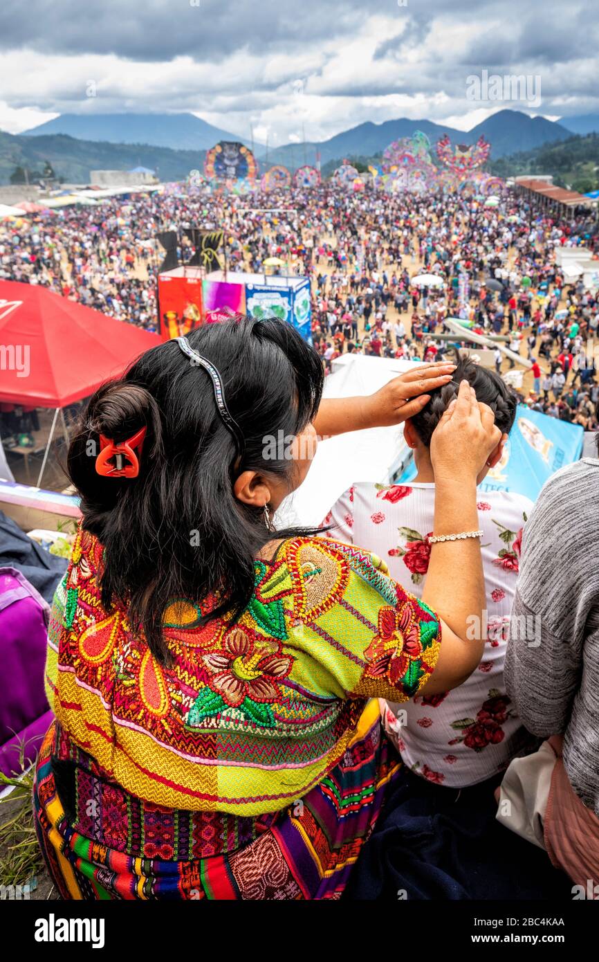 Una madre aiuta i capelli della figlia al Sumpango Kite Festival durante il giorno dei morti in Guatemala. Foto Stock