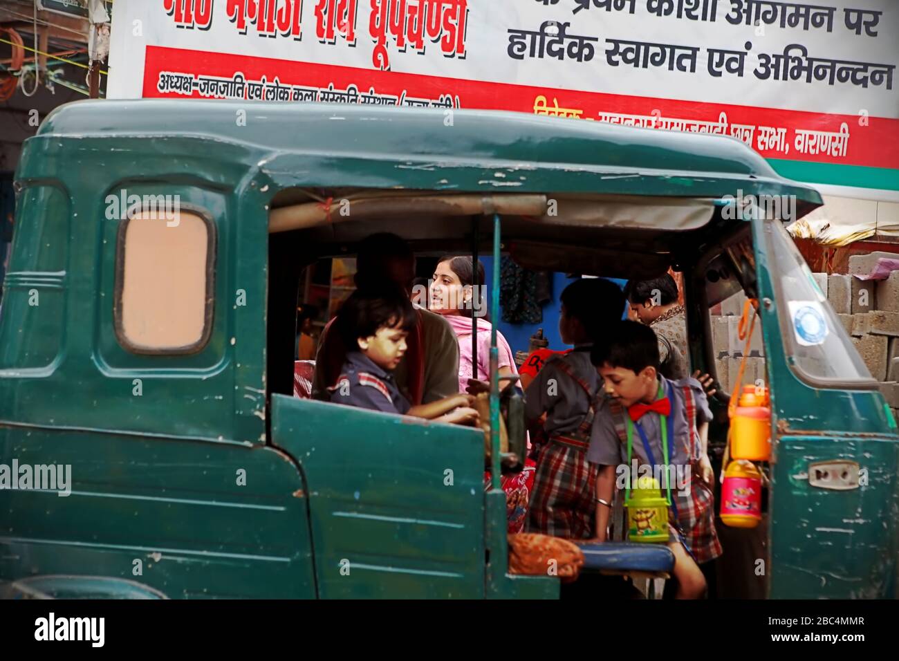 I bambini che salpano in risciò automatico su un lato della strada di Varanasi, Uttar Pradesh, India. Foto Stock