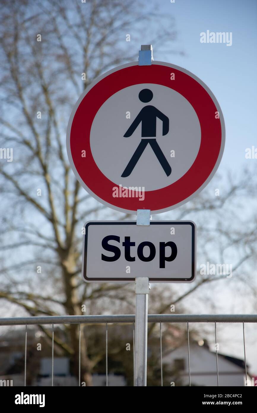 Un cartello circolare su strada bianco e rosso con un uomo nero al centro e un cartello aggiuntivo: Nessun pedone può procedere, fermarsi Foto Stock