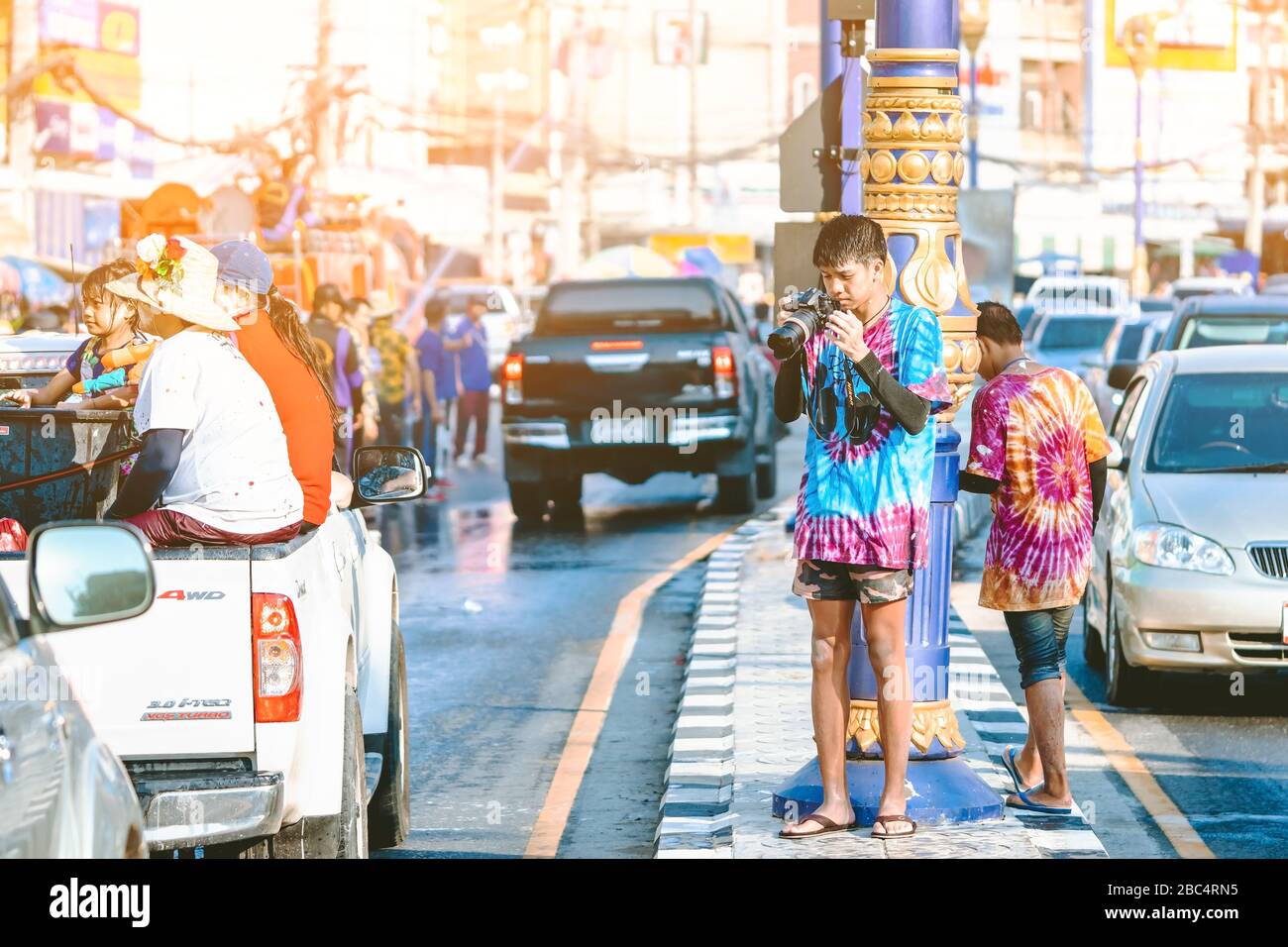 KANCHANABURI, THAILANDIA - 17 APRILE 2019: Giovane fotografo non identificato in abiti bagnati utilizza la fotocamera DSLR per scattare foto di Songkran spruzzi d'acqua fe Foto Stock