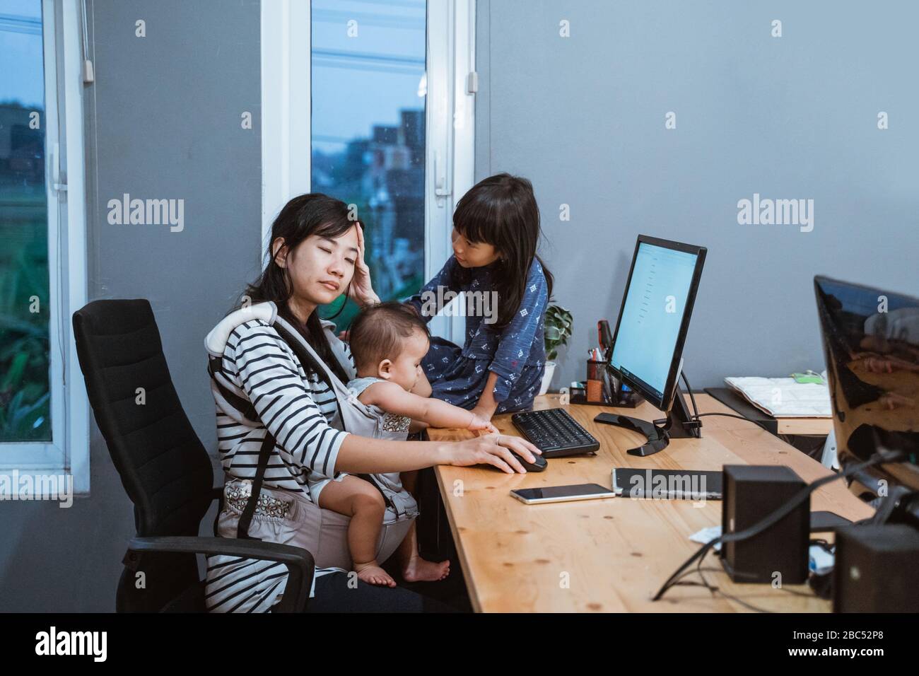 stress madre mentre lavora da casa e baby sitting i suoi figli Foto Stock
