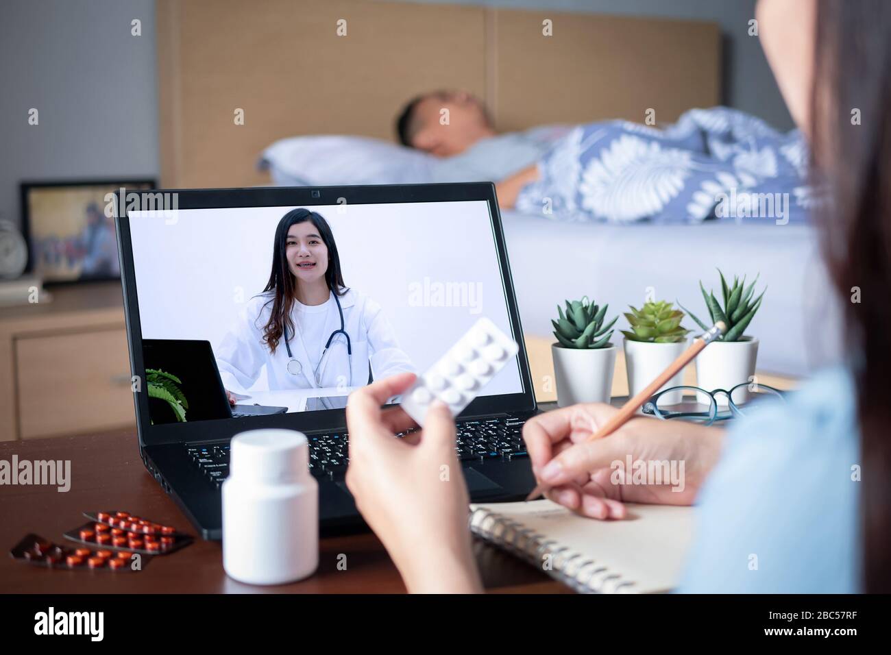 I parenti del paziente usano la video conferenza, fanno la consultazione in linea con il medico sul computer del notebook, chiedono al medico circa la malattia, il farmaco via video c Foto Stock