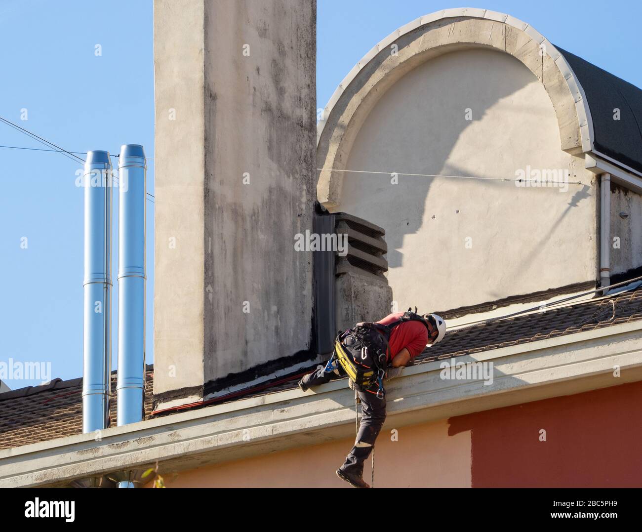 il muratore esegue la manutenzione di una facciata di un edificio e la pulizia delle canne Foto Stock