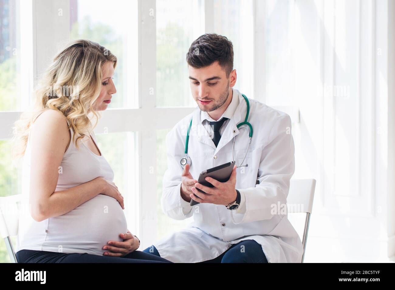 Donna incinta che visita il medico giovane Foto Stock