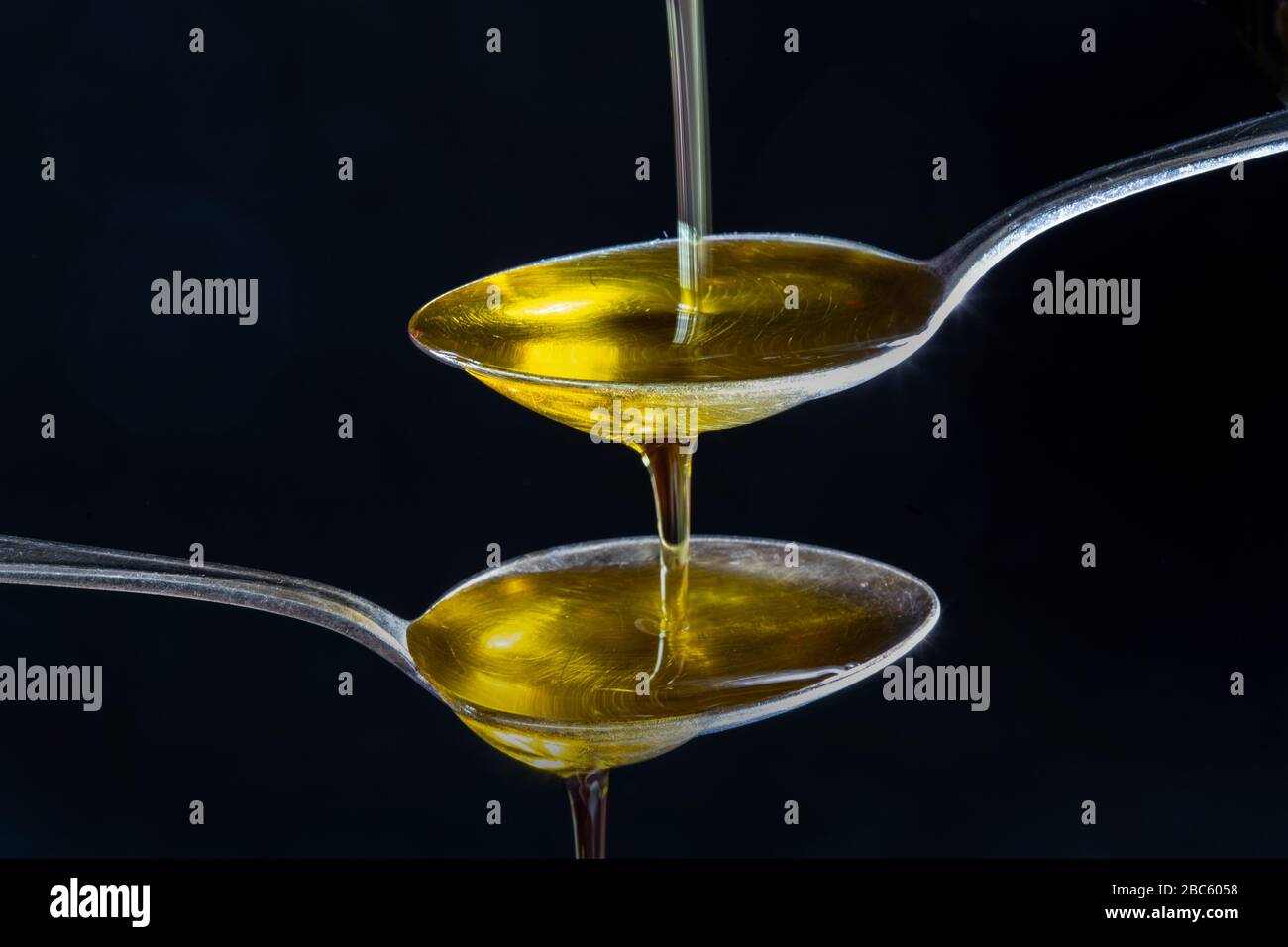 olio d'oliva fluito in piccoli cucchiai Foto Stock