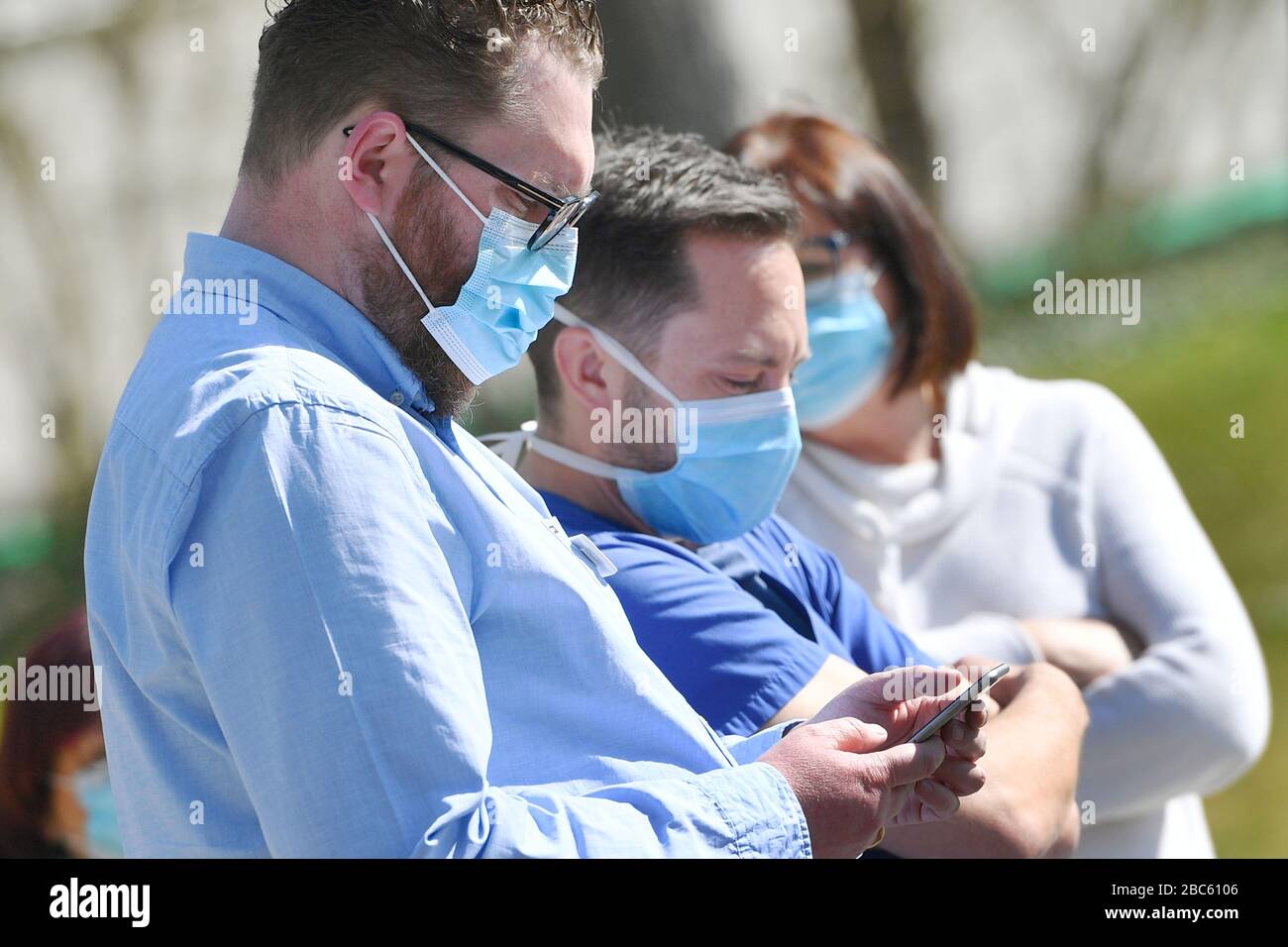 Persone con maschere facciali, maschere facciali, maschere, maschere protettive. Un uomo guarda il suo smartphone, app di tracciamento, app di tracciamento, app per cellulare. Troppe infezioni da corona: Muenchner Helios Klinik cede le operazioni quotidiane. A causa di un gran numero di infezioni da corona tra pazienti e dipendenti, il Muenchner Klinik cede temporaneamente le normali operazioni ospedaliere. Anche la sala d'emergenza è interessata. Le catene di infezione sono da rompere il 2nd aprile 2020 | uso in tutto il mondo Foto Stock