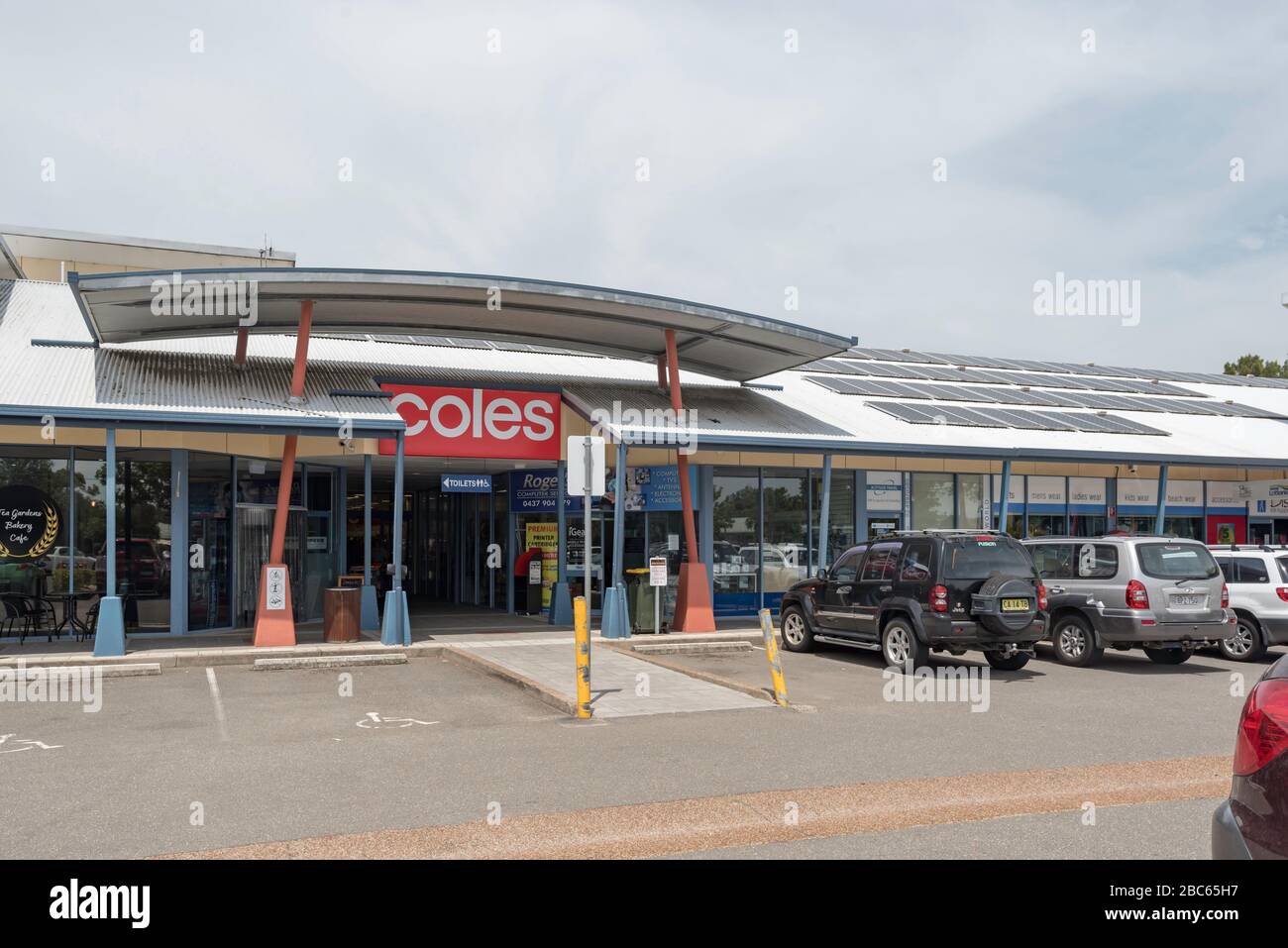 Auto parcheggiate fuori da un supermercato rurale Coles in un edificio con pannelli solari multipli sulla costa medio-settentrionale del nuovo Galles del Sud in Australia Foto Stock