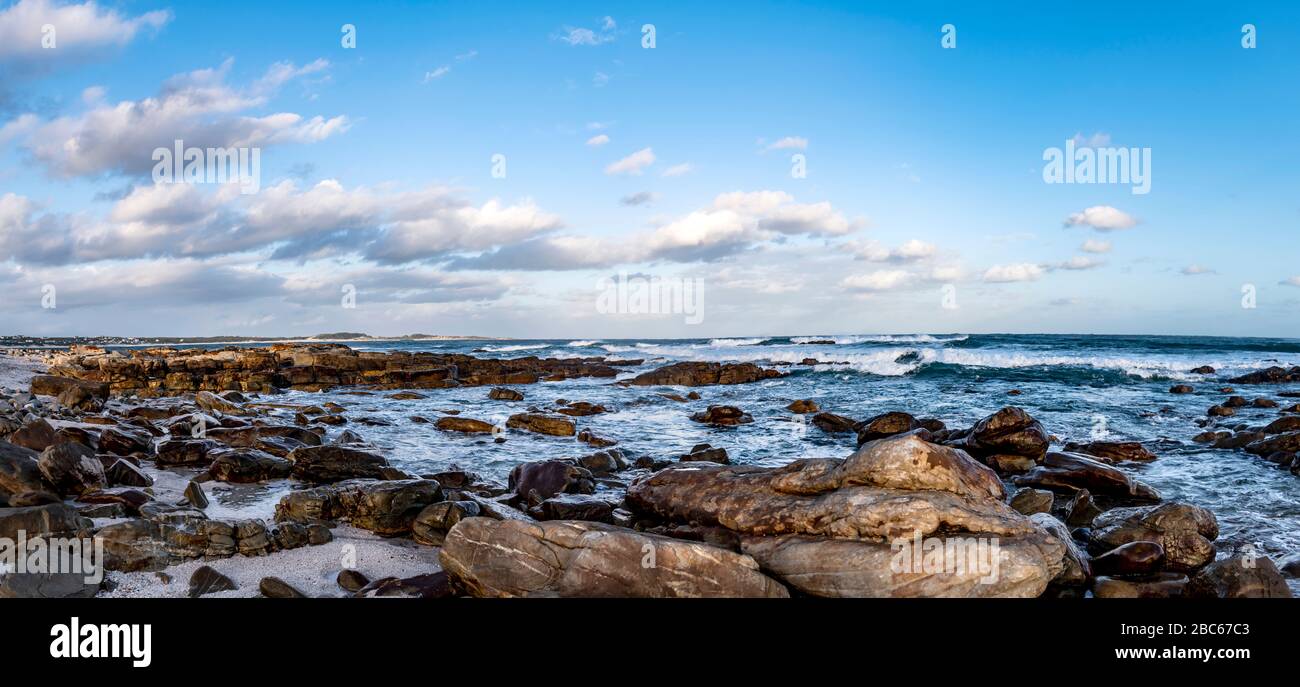 Il Sud Africa, Cape St Francis, il Sole che scende, oltre l'Oceano Indiano e le onde stanno suonando sulle rocce. Foto Stock