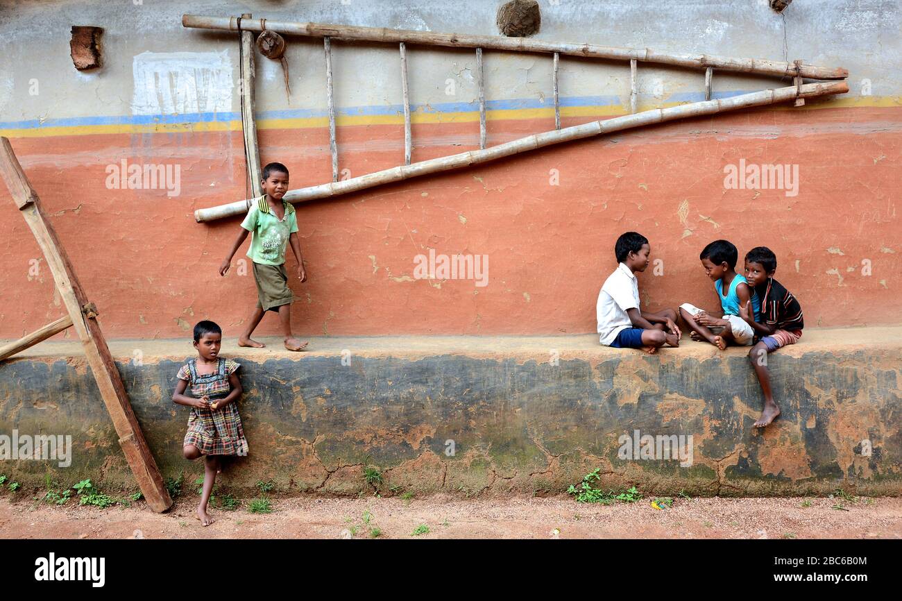 I bambini del villaggio remoto stanno giocando al loro mondo. Uno di loro disegna un'immagine sulla parete di argilla. Foto Stock