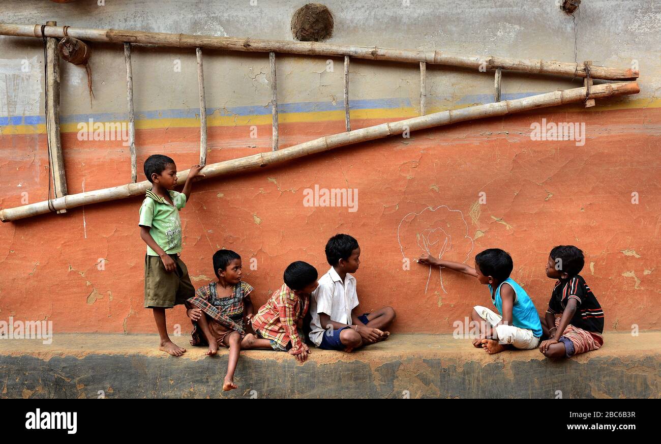 I bambini del villaggio remoto stanno giocando al loro mondo. Uno di loro disegna un'immagine sulla parete di argilla. Foto Stock