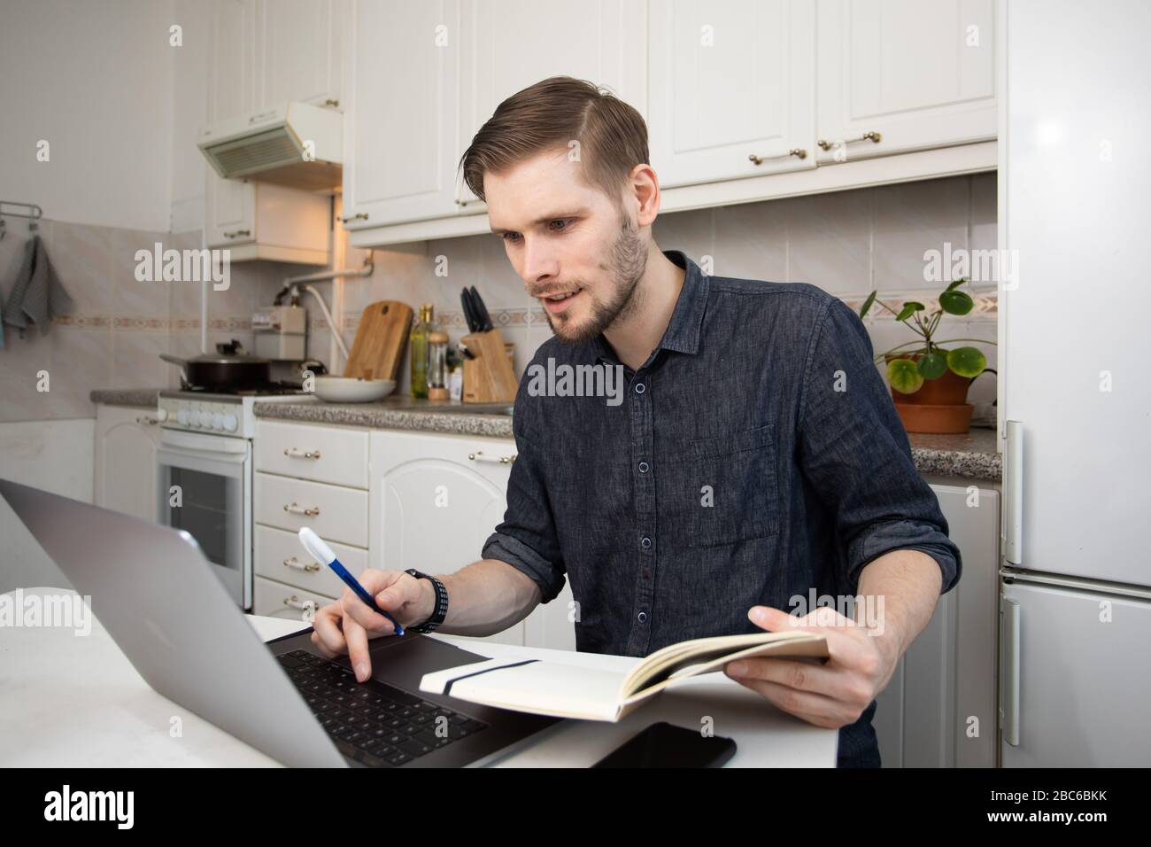Lavorando da casa durante lo scoppio di Coronavirus. Felice uomo freelancer che lavora da casa. Ritratto di uomo seduto alla sua scrivania nel piccolo kit appartamento Foto Stock